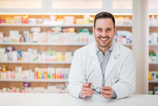 portrait cheerful handsome pharmacist leaning counter drugstore 109710 1738